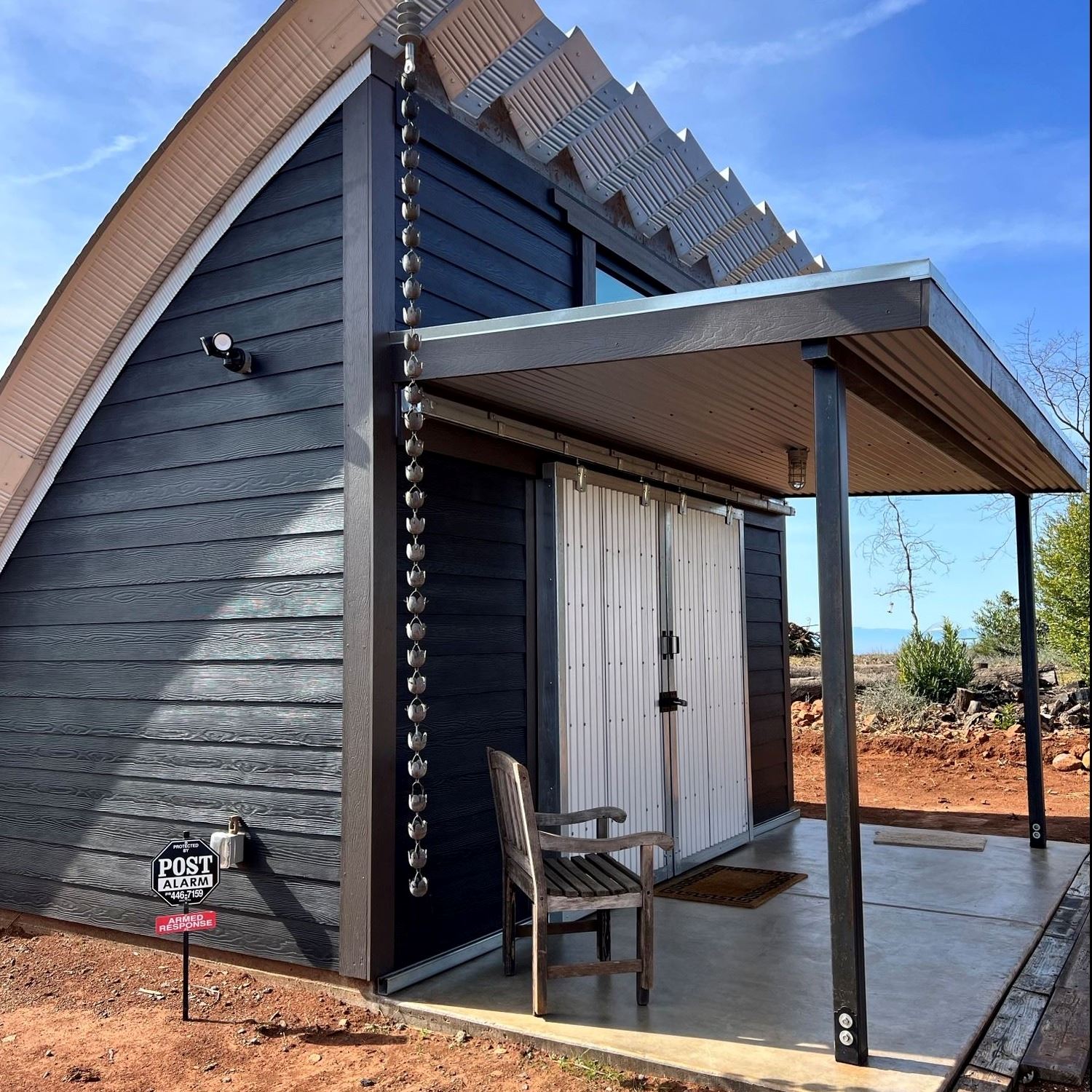 A blue gray quonset hut style ADU with a covered patio