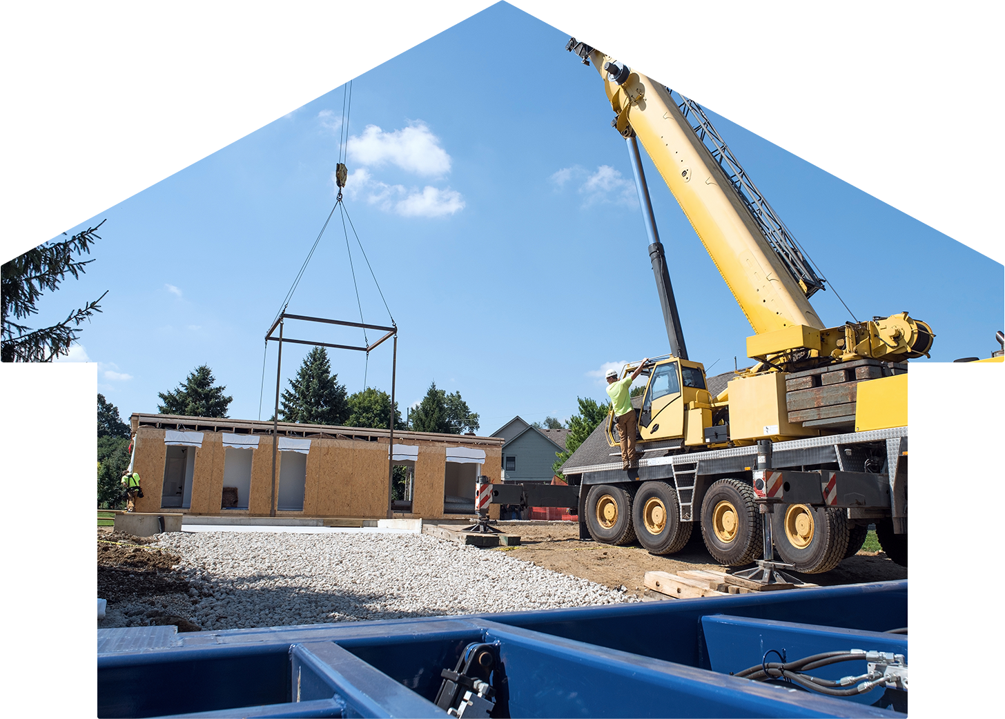 Yellow crane places a pre-fabricated ADU  with two construction workers