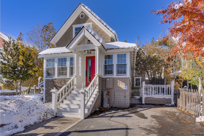 Brick house with a red door and white steps in snow.